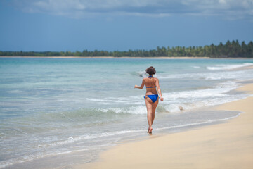 Fototapeta na wymiar Happy female woman enjoying sunny day on the tropical caribbean sandy beach landscape with turquoise sea and blue sky. Freedom concept 