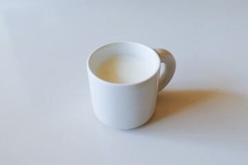 白いテーブルの白いマグカップと白いミルク