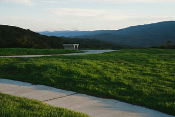 a lone bench with a grassy view of mountains and sky 