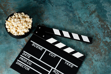 Clapper board with popcorn. Movie concept. Clapperboard on a textural background. Close-up. Copy...