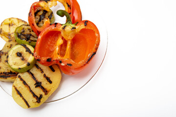 vegetarian lunch, grilled vegetables lying on a transparent plate on a white background close-up