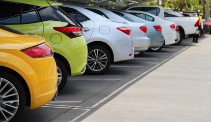 Closeup of rear, back side of orange color car with other cars parking in indoor parking area in...