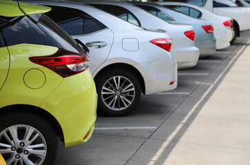 Closeup of rear, back side of yellow car with other cars parking in indoor parking area in bright sunny day. 