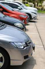 Fototapeta na wymiar Closeup of front side of bronze car with other cars parking in outdoor parking area. Vertical view.