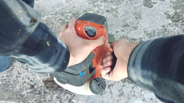 Gardener man start grass trimmer cutter mower. hand pulls the lever