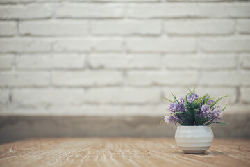 Close up of small purple flower on a white pot with white brick.