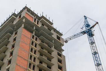 Construction of a multi-storey residential building. Monolithic-brick technology of building floors. High-rise construction crane. Concept of buying an apartment in a mortgage, housing loans.