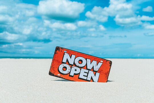Now open sign board stand on sand summer beach background metaphor to time to travel relax tourism season with copyspace.