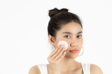 Pretty beauty young Asian woman cleaning her face with cotton pad over white isolated background. Healthy skin and cosmetics concept.