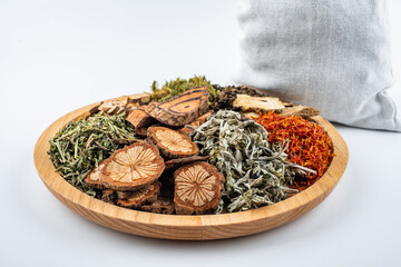 Chinese herbal medicines and medicine packs in a dish with feet on a white background