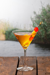 a delicious looking cocktail with a skewer with cherries and pineapple bits on a wooden table
