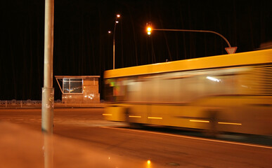 Moving yellow city bus at traffic light at night. Night traffic light
