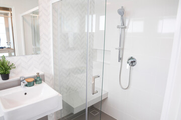 Shower room with chrome tap, transparent glass doors and a shelf. Apartment or hotel room. 