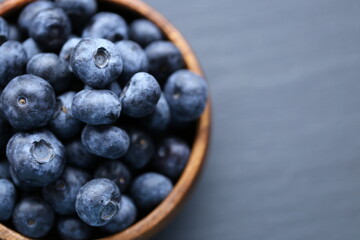  Blueberry berry in a wooden round cup close-up on a black slate background. bio natural dessert and snack.Vegetarian and vegan food. blueberries season.