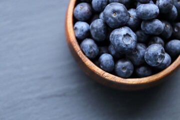  Blueberry berry in a wooden round cup  on a black slate background.Healthy bio natural dessert and snack.Vegetarian and vegan food. blueberries season.