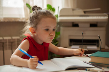 The girl looks indignant in front of herself while studying lessons. International Literacy Day. Education and science. Distance learning. Preschool education.