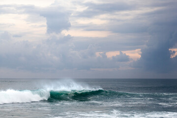 Powerful isolated green wave breaking during sunset with offshore winds in Bali, Indonesia. 