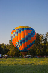 Kyiv, Ukraine - 06/26/2020: Hot air balloon in clear summer sky over trees. Colorful balloon on summer landscape background. Summer leisure. Hot air balloon in flight in the morning.