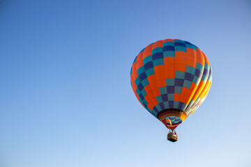 Kyiv, Ukraine - 06/26/2020: Hot air balloon in clear summer sky. Colorful balloon on blue background. Bright geometric design. Summer adventure and leisure. Aviation sport concept.