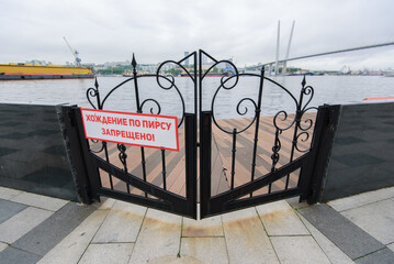 Gates covering the exit to the sea pier. Words in Russian: "Access to the pier is prohibited"