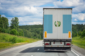 A  truck with the national flag of Guatemala. depicted on the back door carries goods to another country along the highway. Concept of export-import,transportation, national delivery of goods
