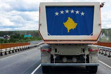 Big dirty truck with the national flag of Kosovo moving on the highway, against the background of...