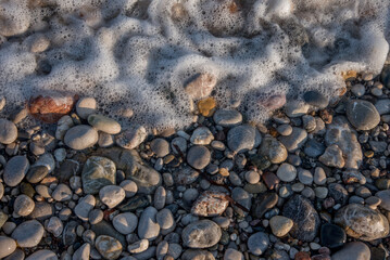Auslaufende Welle trifft einen Kieselstrand