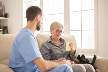 Fototapeta premium Male doctor helping senior woman taking her medicine for her ill.