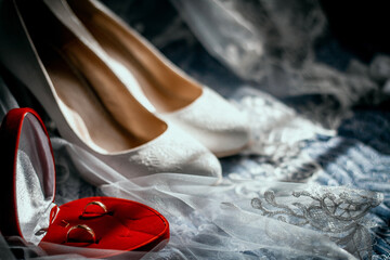 Wedding beige shoes of the bride and wedding rings on the background of a veil