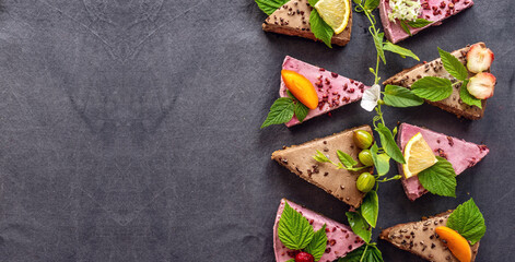 Appetizing pieces of raw mousse cakes, decorated with fruits, berries, flowers and green leaves....