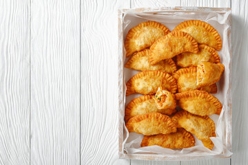 deep fried empanadas on a wooden tray