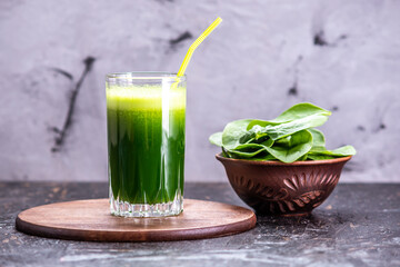 Glass with a vegetarian smoothie from green leaves of fresh spinach. Popular detox drink for healthy eating