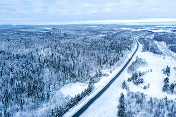 Aerial view on the road and forest at the winter time. Natural winter landscape from air. Forest under snow a the winter time. Landscape from drone