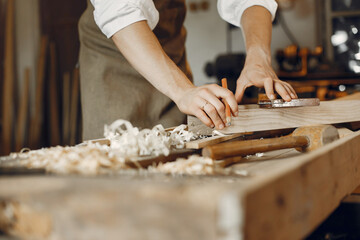 Fototapeta na wymiar Man working with a wood. Carpenter in a white shirt
