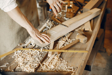 Man working with a wood. Carpenter in a white shirt