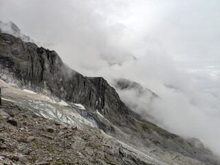 white heavy clouds covered the black mountain with glacier 