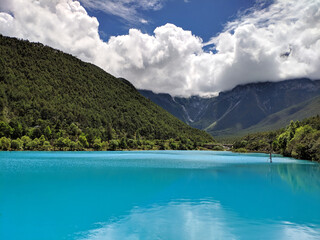 blue lake and green mountains under the white clouds in sunny day