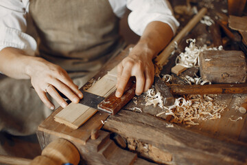 Man working with a wood. Carpenter in a white shirt