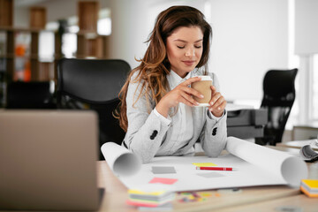 Beautiful young woman with cup of coffee. Woman enjoys fresh coffee in the morning on her desk at the office.	
