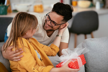 Husband surprising his wife with a gift. Young man giving gift box to his wife.	