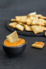 La Gomera cheese paste Almogrote in black ceramic bowl  with crusty crackers on stone cut board at the restaurant table, famous starter  that served in many restaurants in Canary Islands