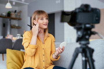 Female vlogger recording makeup tutorial for her channel. Young beautiful woman recording make up...