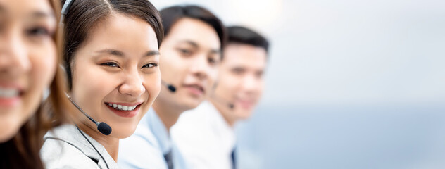 Smiling cheerful Asian woman working in call center office with team as customer service operators,...