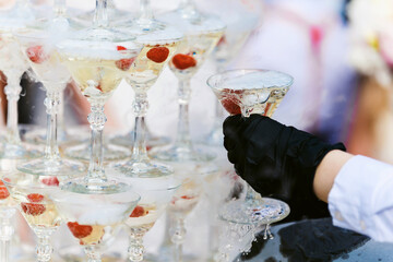 Champagne slide. Pyramid or fountain made of champagne glasses with cherry and steam from dry ice