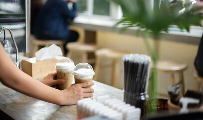 Close up of hand. barista holding ice coffee in plastic cup server for customer