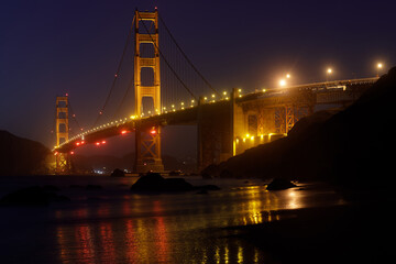 Fototapeta na wymiar Golden Gate Bridge and Reflections Glow in the Dark, via Marshall's Beach 