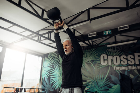 Senior Man Exercising At Gym. Mature Man Exercising With Kettle Bell.