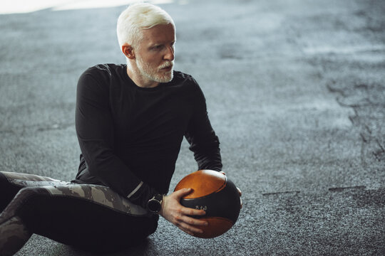 Senior Man Exercising At Gym. Mature  Man Exercising With Medicine Ball.