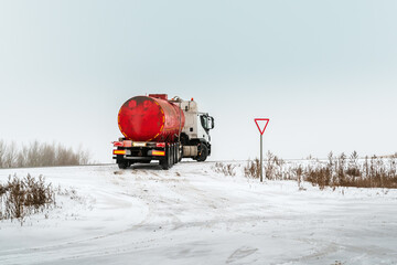 Oil truck with a red tank truck drives onto the main road