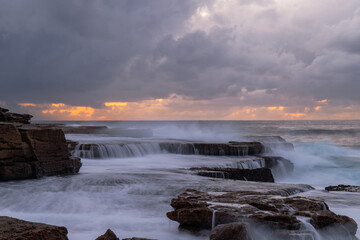 Cloudy view of rock formation on the shore.